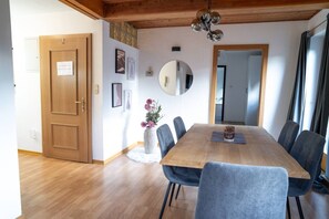 A dining area with a wooden table, blue chairs, a vase with flowers, a mirror, and a wooden ceiling. - Faraway Homes Studio St. Wolfgang #6 (Ried)