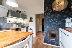 Eine moderne Küche mit Holzarbeitsplatte, weißen Schränken und einer Tafelwand mit Beschriftungen.