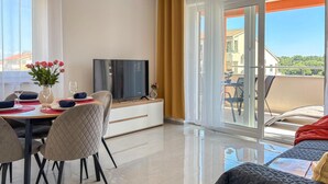 Uma sala de estar moderna com área de jantar, televisão e varanda com vista.