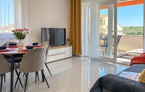 Ein modernes Wohnzimmer mit Essbereich, einem Fernseher und einem Balkon mit Blick.