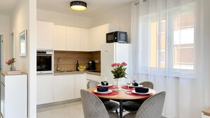 Cozinha moderna com armários brancos, micro-ondas e área de jantar com mesa posta para dois.