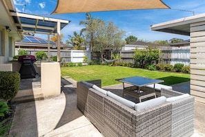 A backyard with a covered patio, a barbecue grill, and outdoor furniture. - Salt & Sand in Seaford (Seaford)