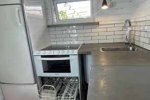 A compact kitchen with a built-in oven, a dishwasher, and a stainless steel sink. - Skummesloev Family Escape L (Skummesloevsstrand)