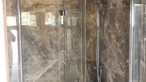 A glass-enclosed shower with a handheld showerhead and a wall-mounted faucet. - Skummeslöv Family Hosue (Skummesloevsstrand)