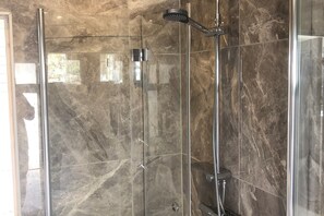 A glass-enclosed shower with a handheld showerhead and a wall-mounted faucet. - Skummeslöv Family Hosue (Skummesloevsstrand)