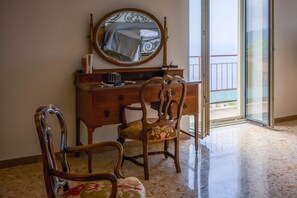 Una habitación con cómoda de madera, una silla, un espejo y vistas al balcón.