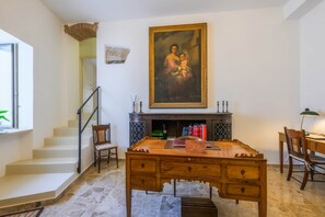 Une piÚce avec un escalier, un bureau en bois, une cheminée et un grand tableau encadré.