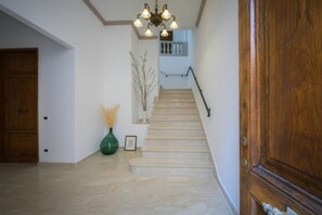A staircase with a handrail, a wooden door, and a vase with dried plants.