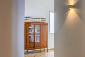 Un mueble de madera con puertas de vidrio, un tablero de libro estampado y una lámpara fijada a la pared.
