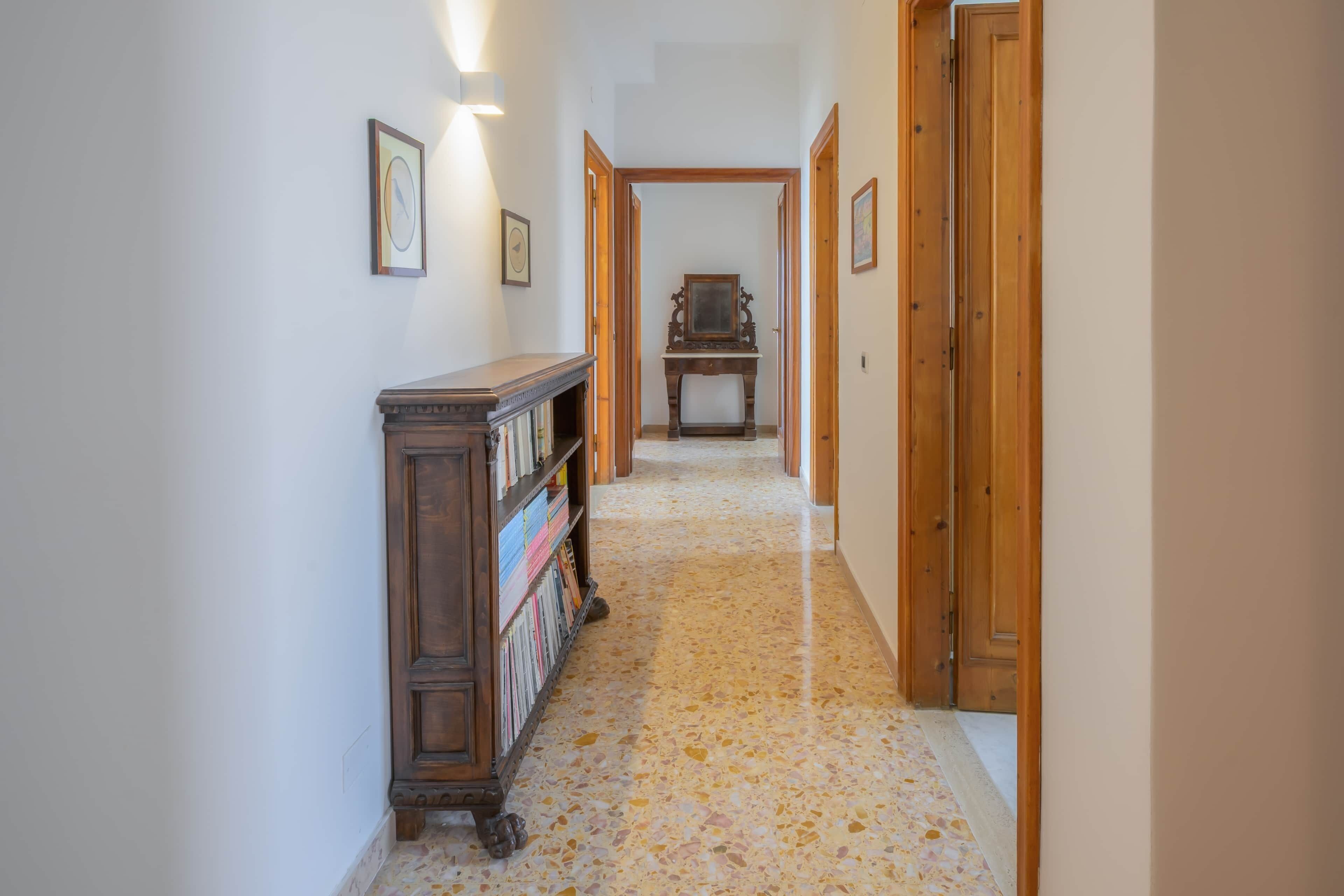 A hallway with wooden doors, a wooden bookcase, and framed pictures on the walls.