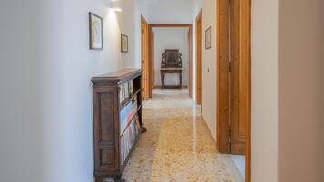 A hallway with wooden doors, a wooden bookcase, and framed pictures on the walls.
