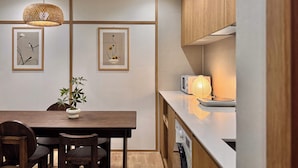 A modern kitchen with wooden cabinets, a dining table with chairs, and two framed artworks on the wall. - ONJAE Stay Seoul Jongno (Seoul)