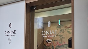 A hotel entrance with a wooden door, a sign reading 'ONJAE STAY JONGNO,' and a floral mural on the wall. - ONJAE Stay Seoul Jongno (Seoul)