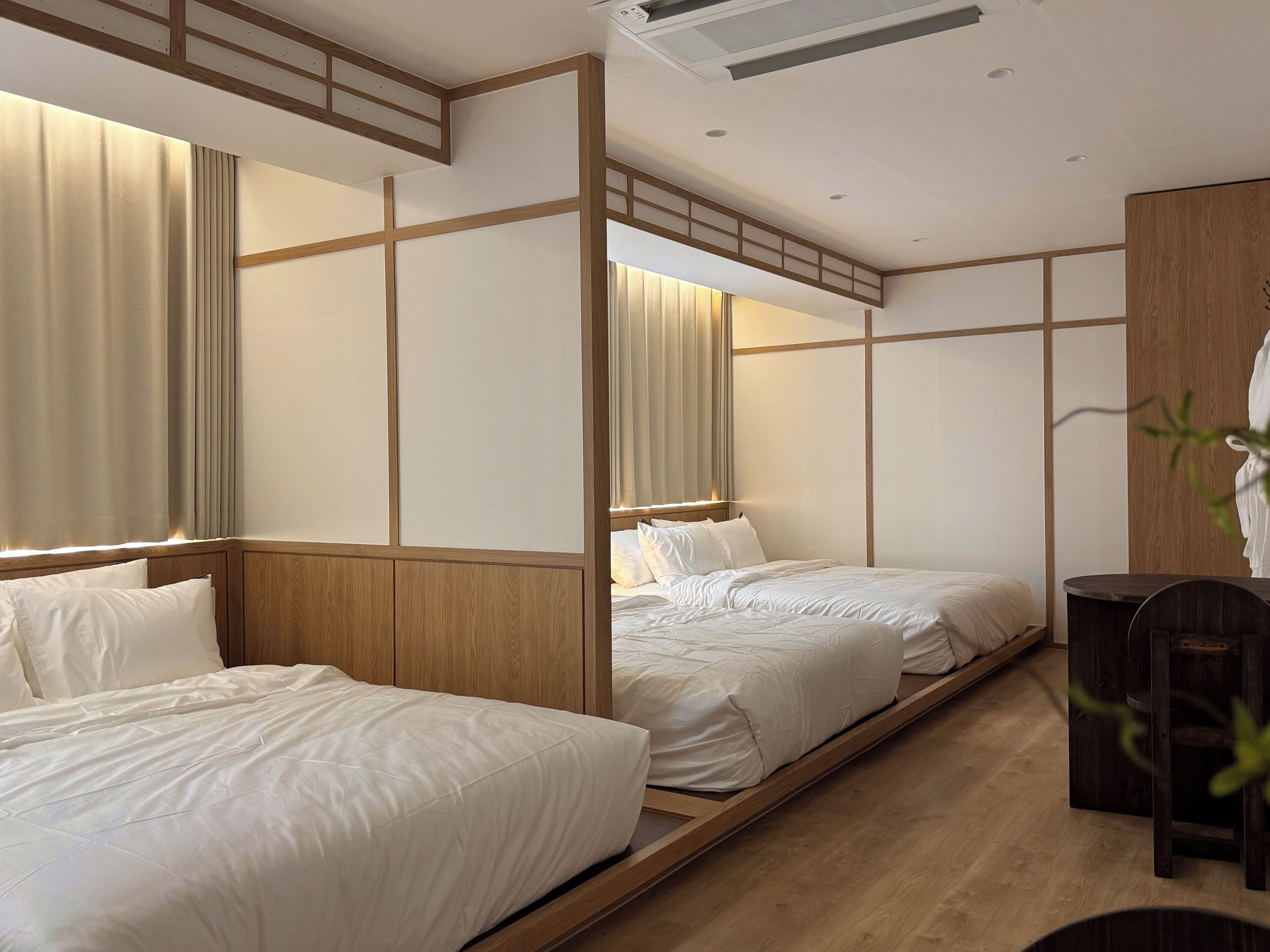 Habitación de hotel con dos camas, paneles de madera y un escritorio.