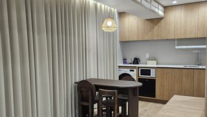 A modern kitchen with wooden cabinets, a dining table with chairs, and a built-in oven. - ONJAE Stay Seoul Jongno (Seoul)