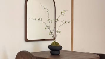 Una mesa redonda de madera con una planta en maceta, una silla de madera y un espejo fijado a la pared.