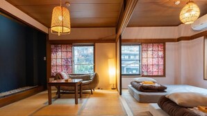 Una habitación tradicional japonesa con suelo de tatami, una mesa baja, un sofá y una cama.