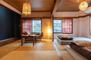 Perinteinen japanilaistyylinen huone, jossa on tatamimatto, matala pöytä, sohva ja sänky.