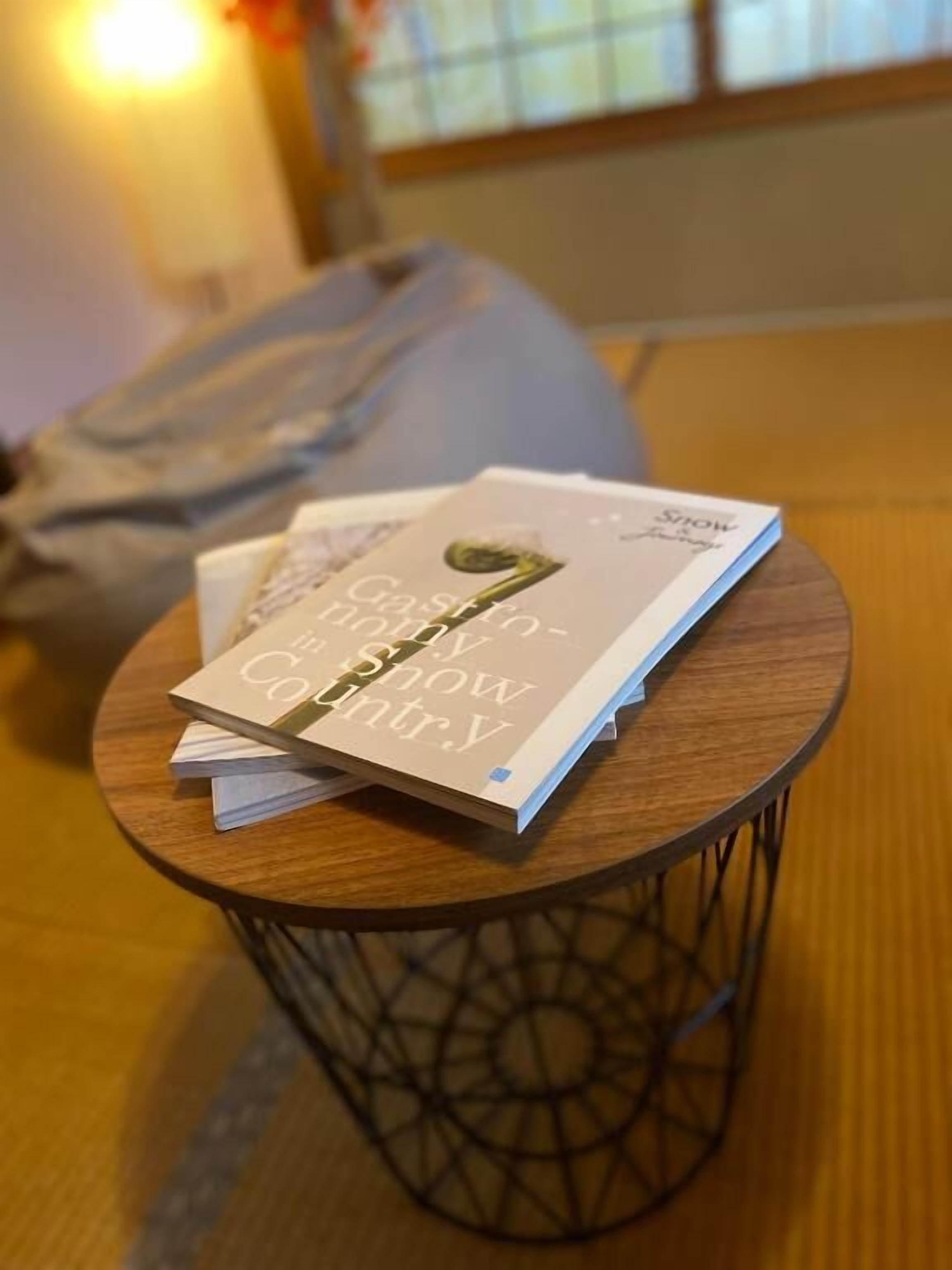 A small round table with a book titled 'Castaway Country' and a bag in the background.