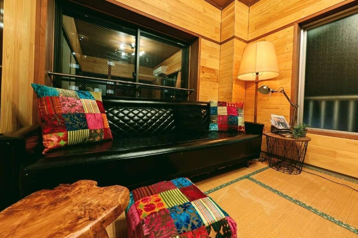A wooden interior with a sofa, cushions, a lamp, and a small table.