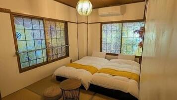 Ein traditionell japanisch gestalteter Raum mit Tatami-Böden, einem Bett mit weißer Bettwäsche und zwei Tatami-Matten auf dem Boden.