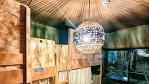 Una habitación con literas, una lámpara colgante esférica y un televisor.