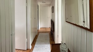Un pasillo con pisos de madera, paredes blancas y puertas que dan a otras habitaciones.