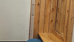 Et hjørneværelse med et træskab, en lille skammel og et vindue.