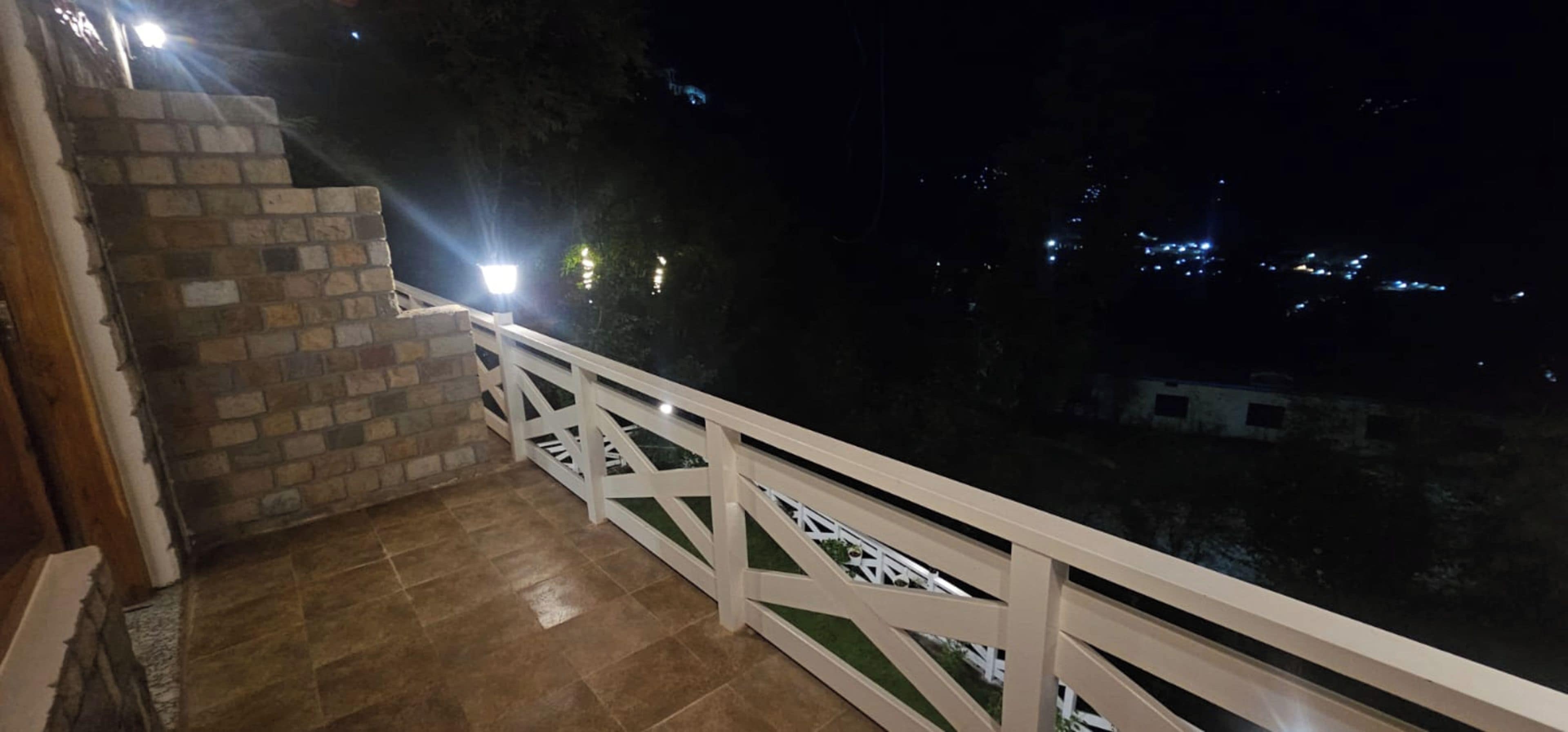 A balcony with a white railing, a brick wall, and a tiled floor.
