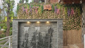 Parede de pedra com elementos de água e uma placa de madeira em cima.