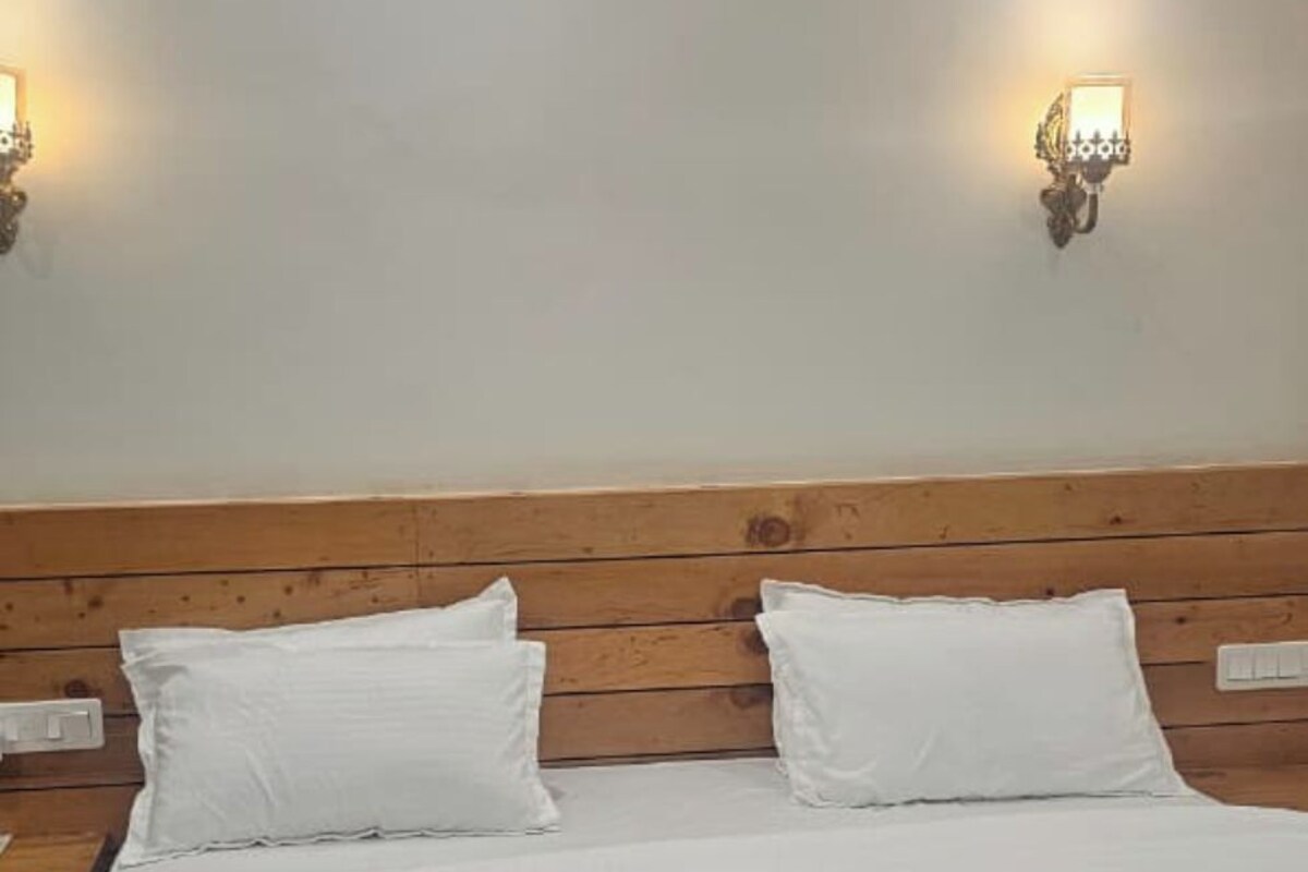 A bed with a wooden headboard, two white pillows, and two wall-mounted light fixtures.