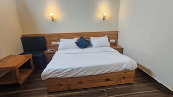 A single-bed room with a wooden headboard, two bedside tables, a bench, and two wall-mounted lights.