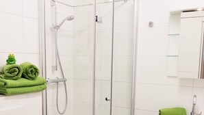 Ett badrum med en dusch som är avskärmad med glasväggar, ett handfat och en toalett.