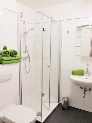 Ein Badezimmer mit Duschkabine, Waschbecken und Toilette.