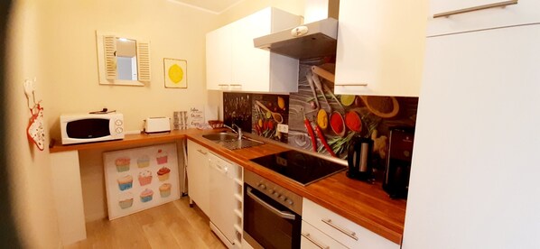 A compact kitchen with a microwave, toaster, sink, and stove. - Vacation apartment Anna (Winterberg)