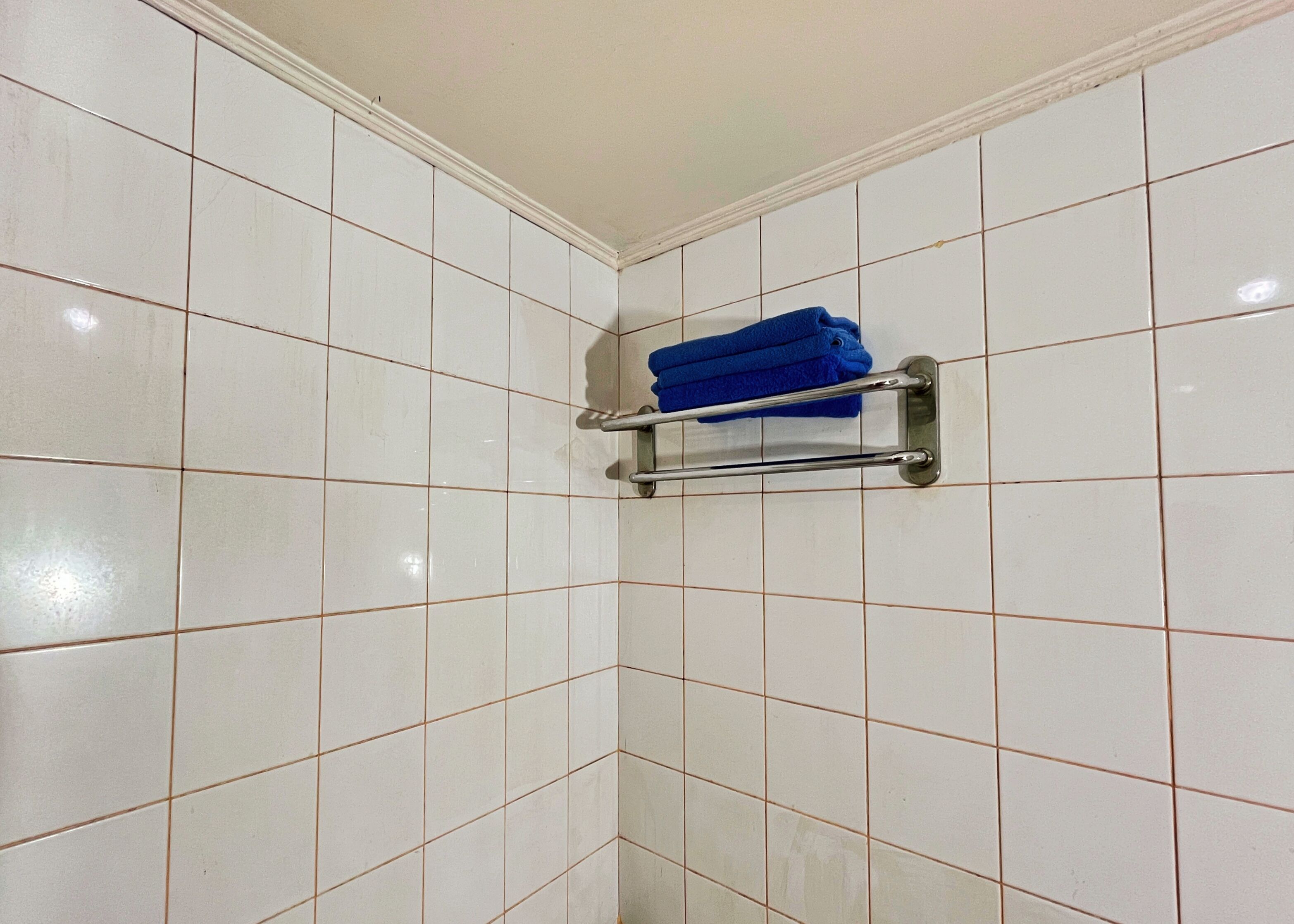 A tiled bathroom with a towel rack holding folded towels.