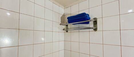 A tiled bathroom with a towel rack holding folded towels.