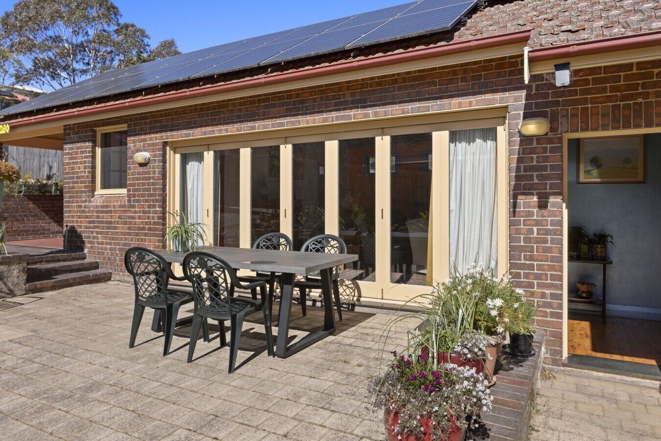 A brick house with a patio, a dining table with chairs, and a large sliding glass door.