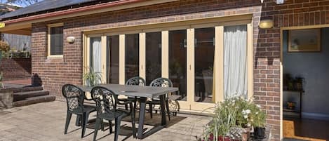 A brick house with a patio, a dining table with chairs, and a large sliding glass door.