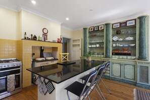 A kitchen with a central island, a stove, and a dining area with chairs. - El Dorado | Sunny Family Home, Walk to Town (Katoomba)