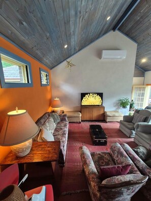 Ein gemütliches Wohnzimmer mit einer Couch, Sesseln, einem Couchtisch und einer Wanddekoration.