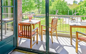 Ein Balkon mit Holzmöbeln, einem Tisch und Stühlen.