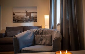 A living room with a sofa, a chair, a lamp, and a painting on the wall. - 1 bedroom lovely apartment in Barth (Barth)