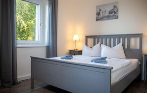 A neatly made bed with pillows and folded towels, a bedside lamp, and a painting on the wall. - 1 bedroom lovely apartment in Barth (Barth)
