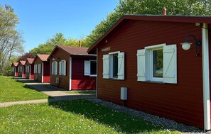 A row of wooden cabins with white shutters, a clear sky, and a grassy area in front. - 1 bedroom lovely apartment in Barth (Barth)