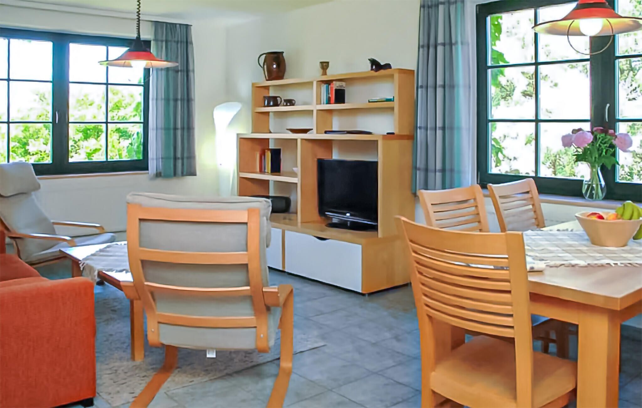 Un salon avec un téléviseur, des chaises en bois, une table à manger et une bibliothèque.