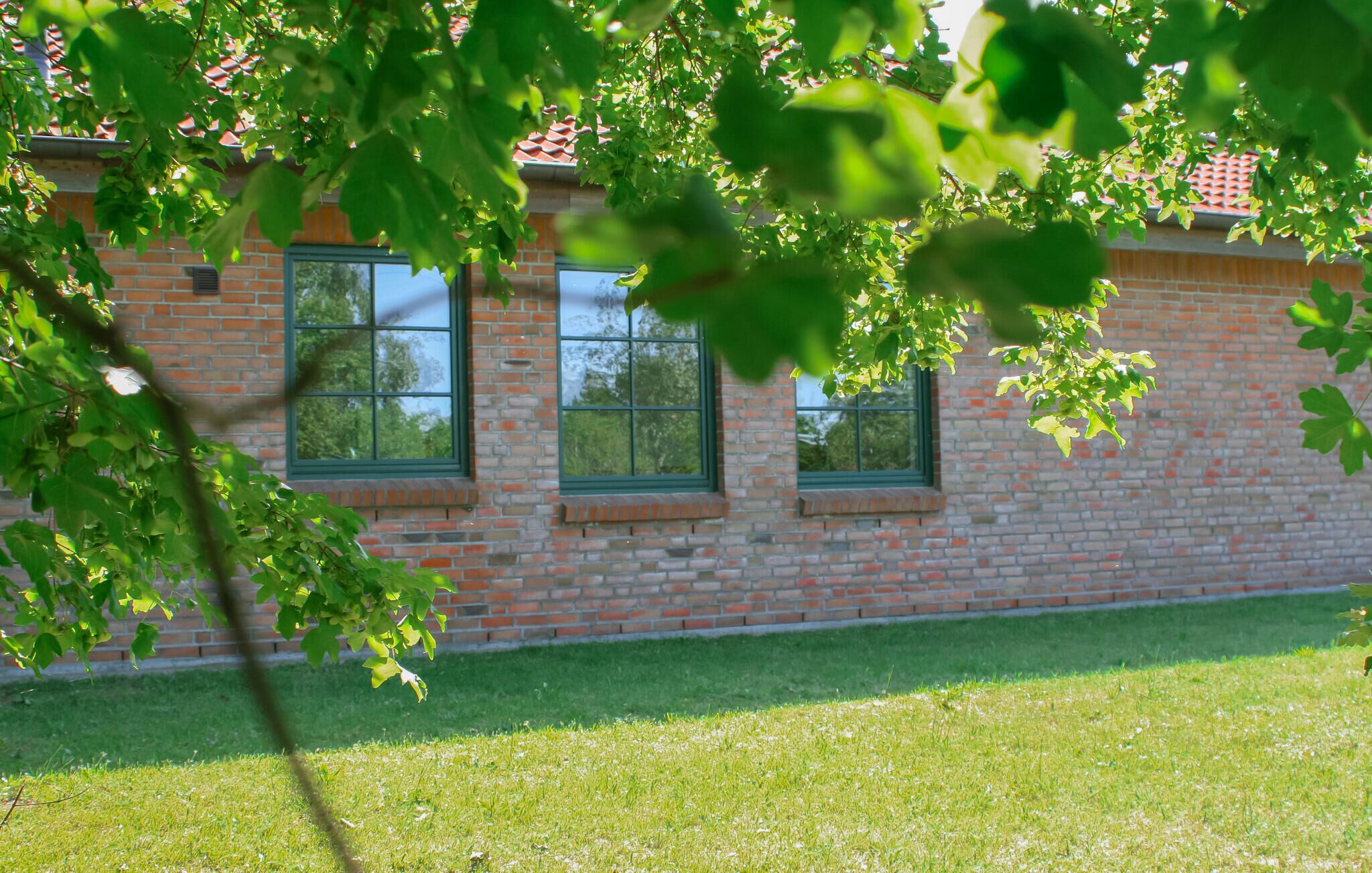 Ein Backsteinhaus mit drei Fenstern und einem grünen Rasen.