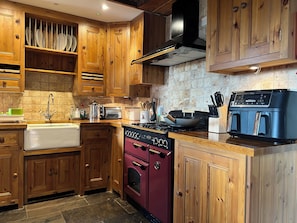 A kitchen with wooden cabinets, a stove, a dishwasher, and a NINIA coffee machine.