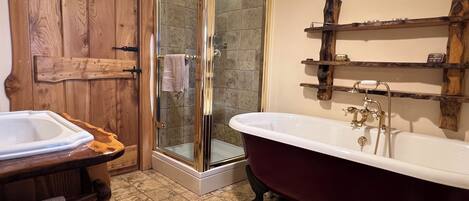 Un baño con una bañera independiente, ducha con mampara de cristal y estanterías de madera.