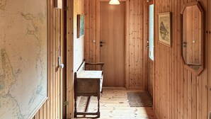 Un corridoio in legno con una panchina, una porta e una lampada a sospensione.